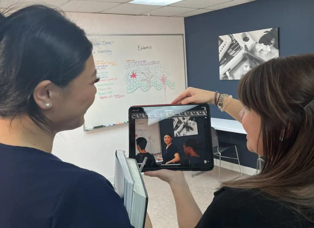 two students looking at a photo on a tablet