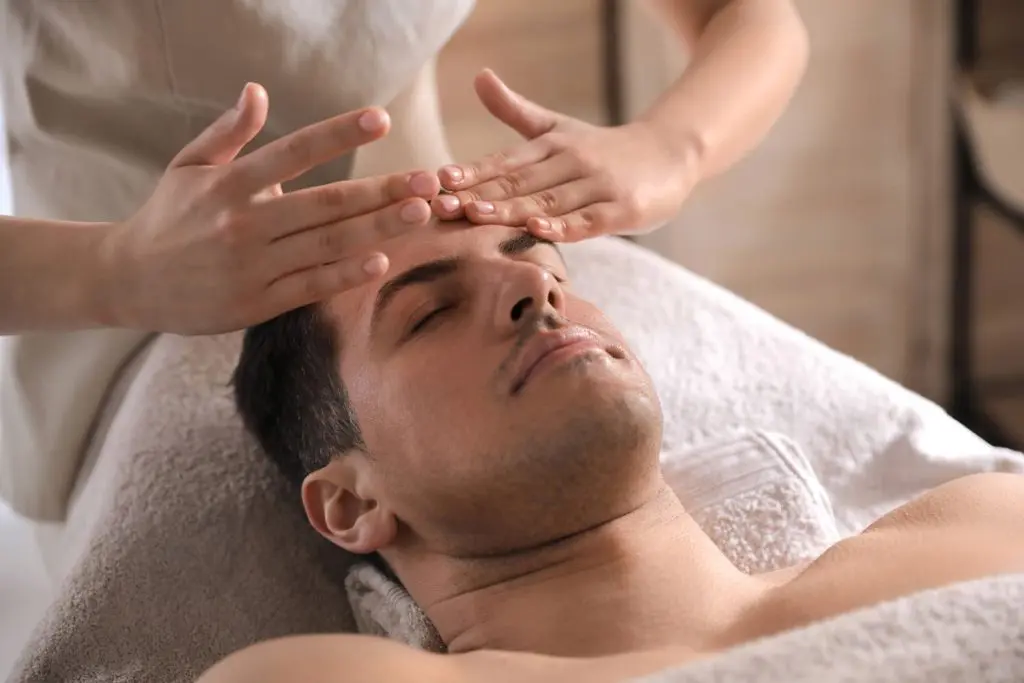 An esthetician gently massages a client's forehead during a facial treatment at Atelier Esthetique, illustrating hands-on training in an esthetician licensing program.