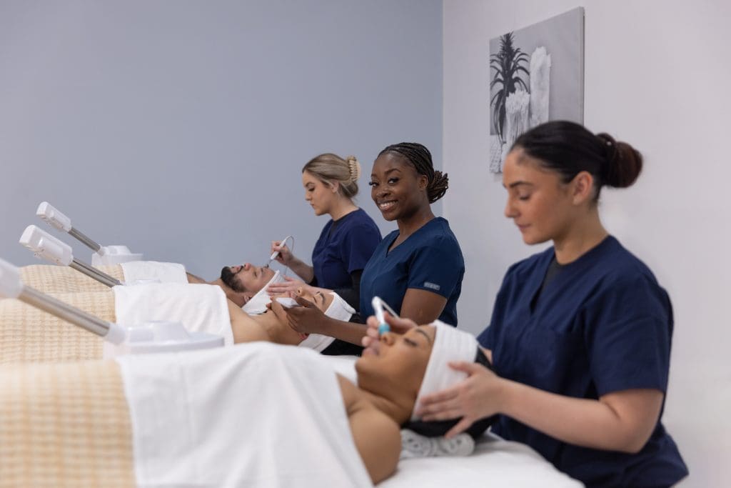 Three students at Atelier Esthetique learning tips for new spa owners